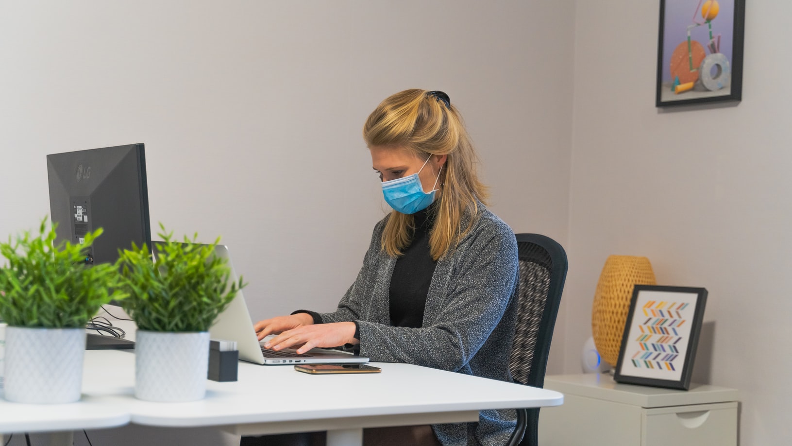 Woman at Her Desk in the Office Wearing a Cloth Mask on the Computer
