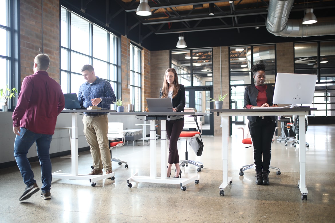 Three Employees at an Office Standing at their Sit-Stand Desks