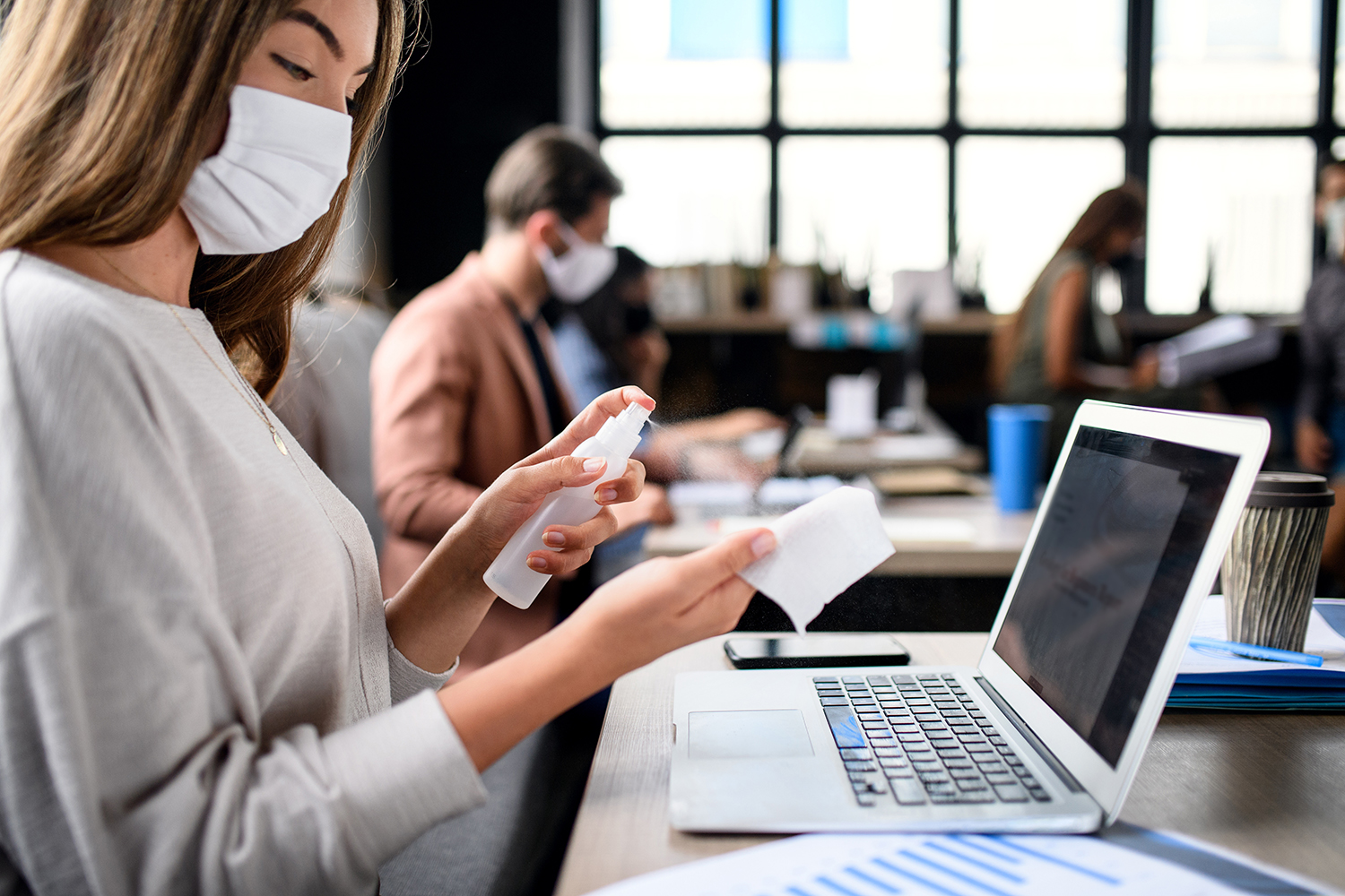 People with face masks disinfecting indoors in office, back to work