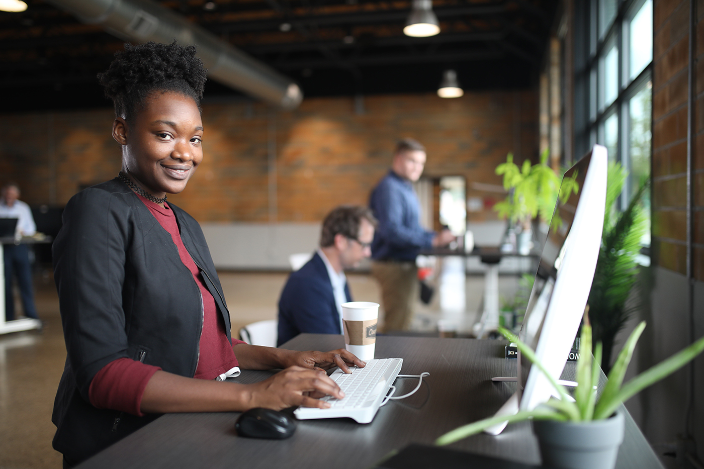 young woman at a sit-stand station young African American woman at a sit-stand desk at work smiling